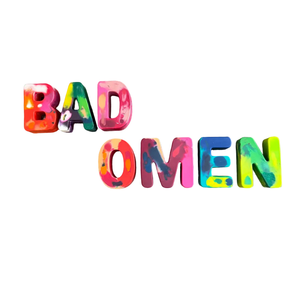 Colorful 3D block letters spelling 'BAD OMEN' on a plain white background.